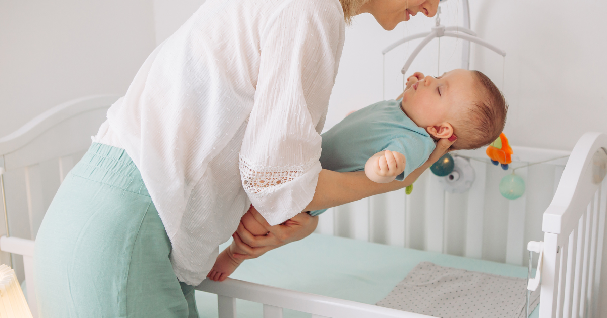mama stavlja bebu u krevetac na spavanje