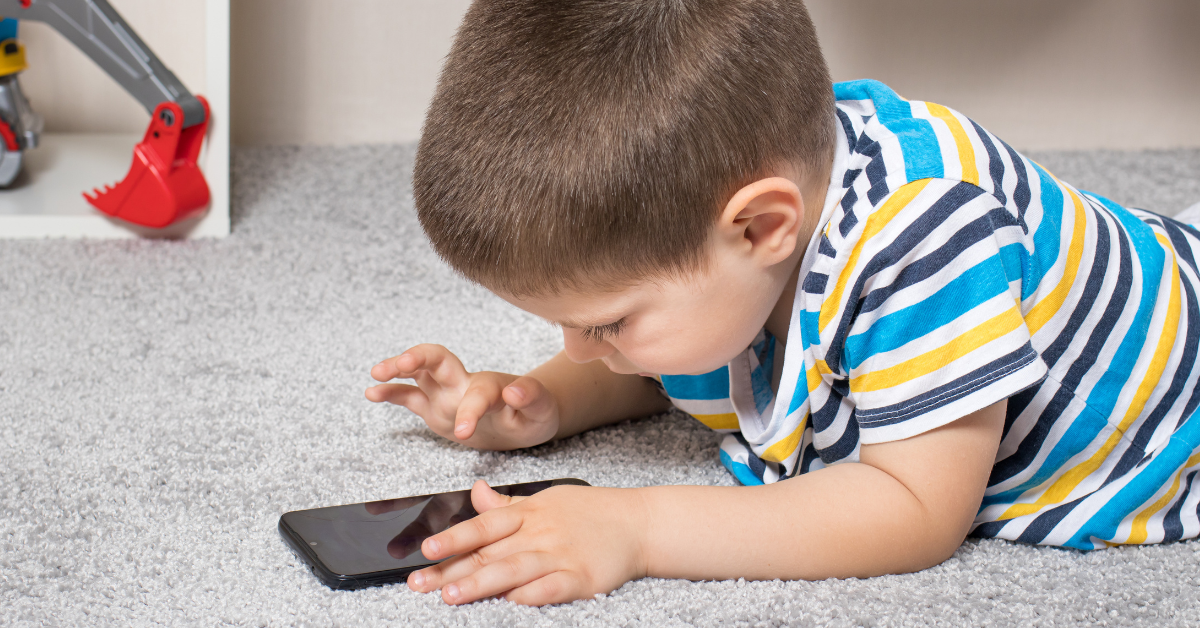 Mali dečak gleda u mobilni telefon