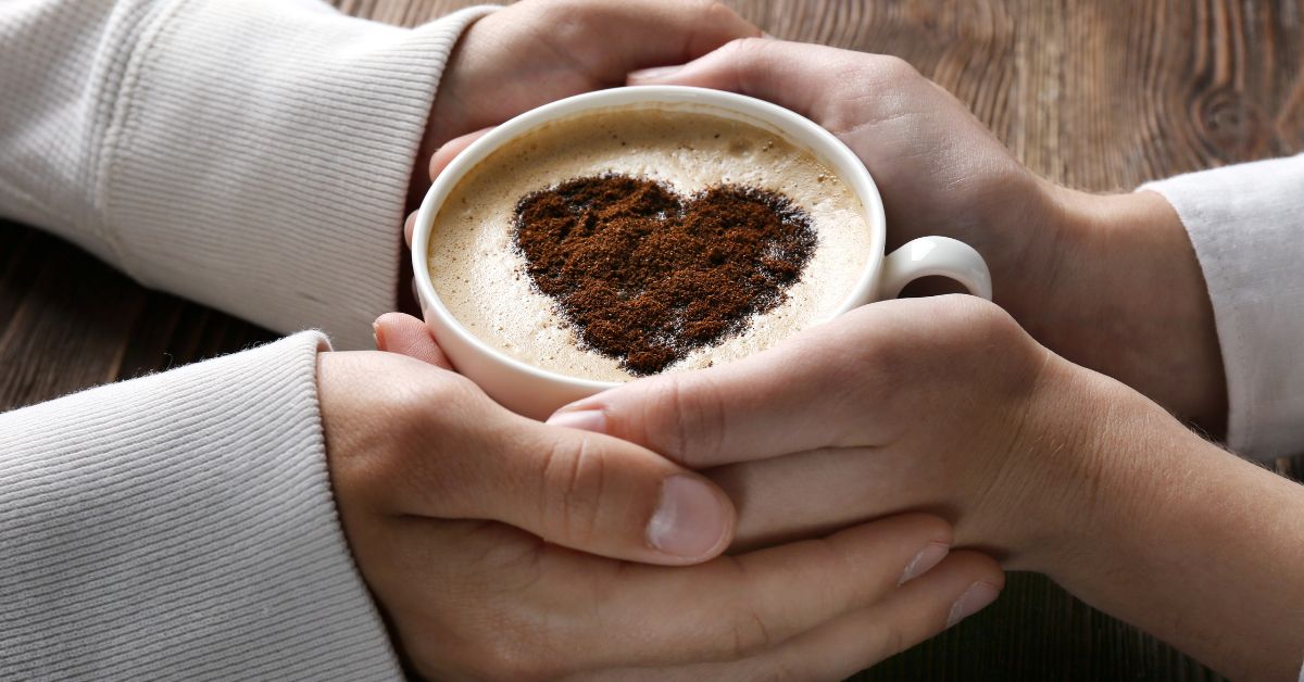 Fotografija muških i ženskih ruku kako drže šolju kafe sa srcem