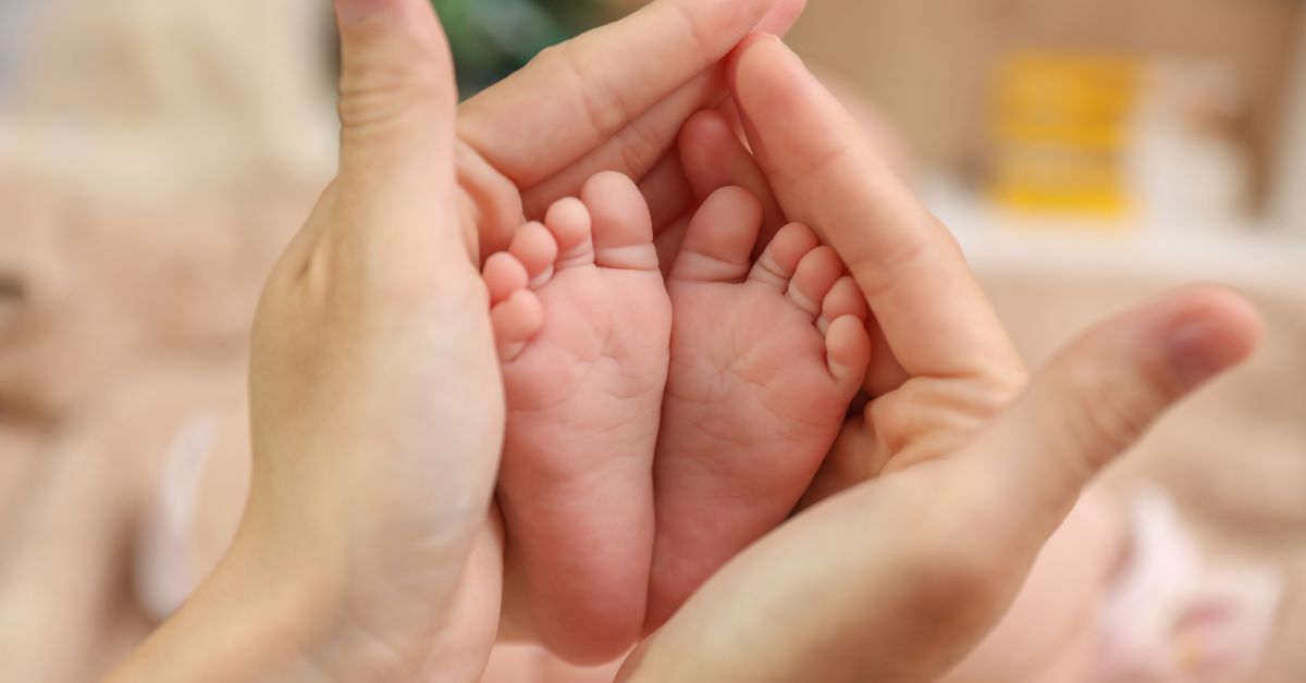 Beba mama drži stopala u šakama